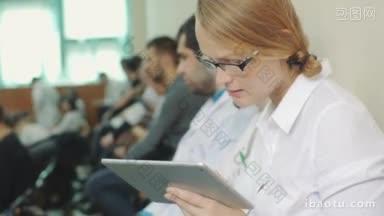 年轻女医生或学生使用平板电脑在医学会议、研讨会或讲座上做笔记